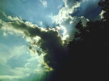 Low angle view of trees against cloudy sky