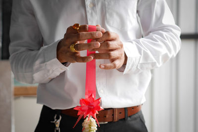 Midsection of man holding ribbon