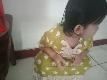 High angle view of girl looking away while standing on floor at home