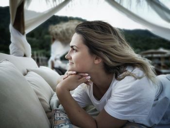 Woman looking away while lying on bed outdoors