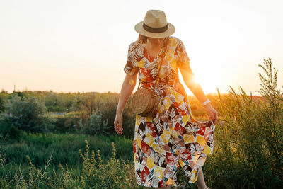 Rear view of woman standing against sky during sunset