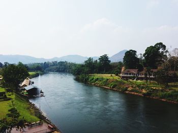 River amidst buildings and trees against sky