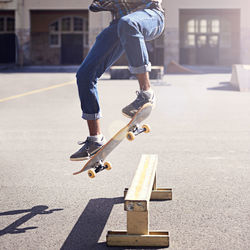 Low section of man skateboarding on road