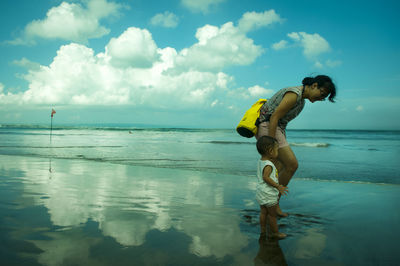 Full length of shirtless man in sea against sky