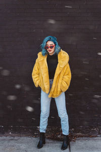 Full length portrait of woman standing against wall during winter