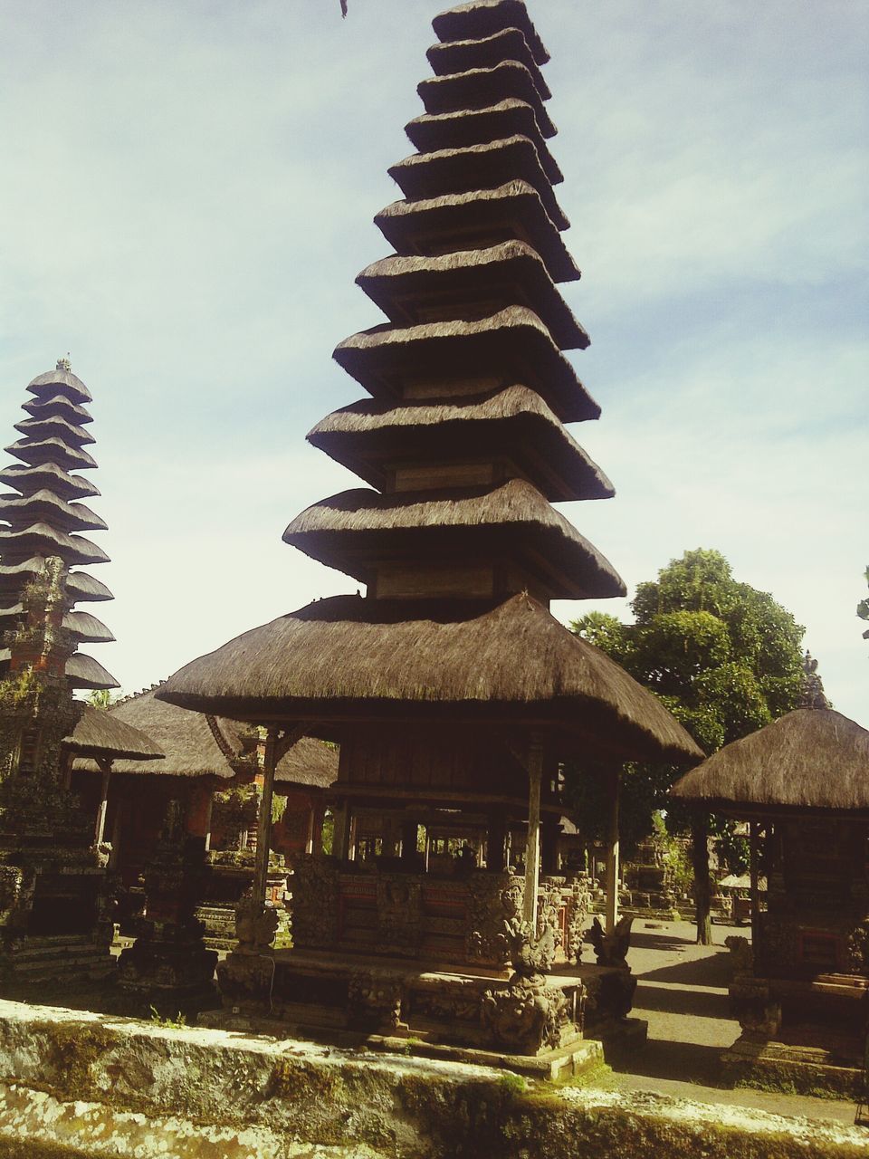 sky, built structure, tree, architecture, building exterior, cloud - sky, low angle view, sunlight, cloud, outdoors, in a row, day, wood - material, thatched roof, nature, tranquility, travel destinations, no people, temple - building, history