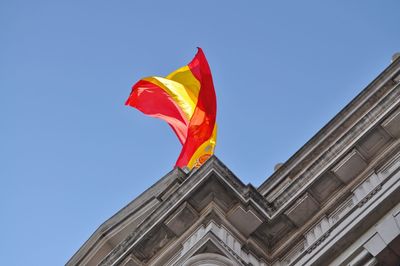 Low angle view of spanish flag on historic building against clear sky