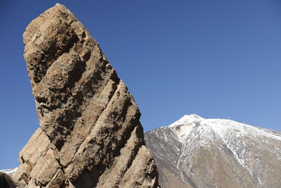 Low angle view of rocks against blue sky