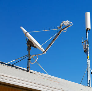 Low angle view of communications tower against clear blue sky