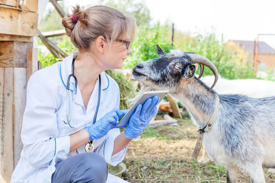 Side view of young woman holding goat