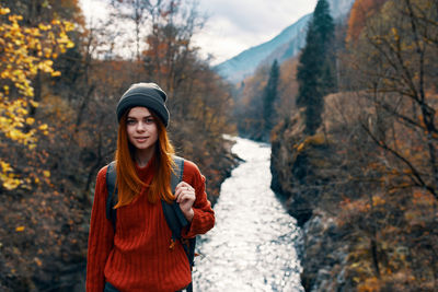 Portrait of smiling young woman standing against trees during winter