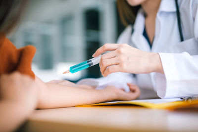 Midsection of doctor giving injection to patient in hospital