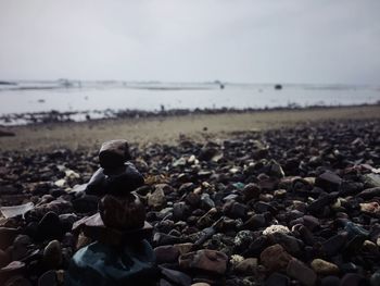Scenic view of pebbles on beach against sky