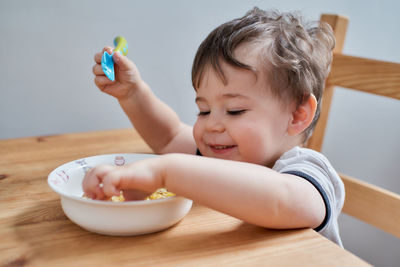 Little boy is eating eggs for breakfast and fooling around making faces