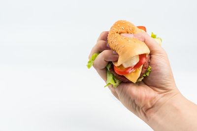 Close-up of hand holding ice cream over white background