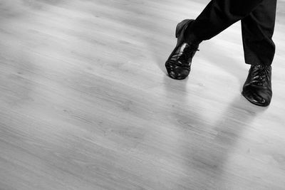 Low section of man wearing shoes on hardwood floor