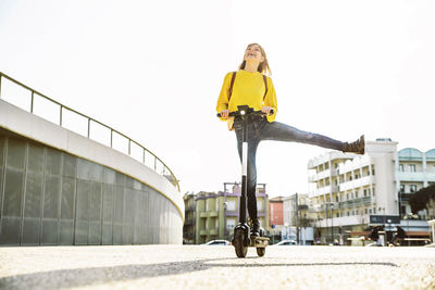 Woman with umbrella on street against clear sky