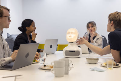 Business people discussing robot voice assistant during meeting