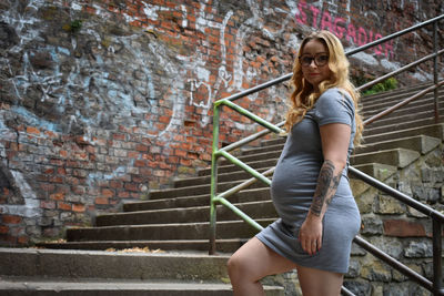 Full length of woman on steps against wall