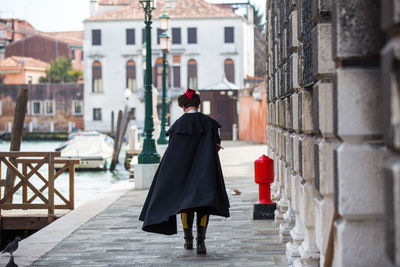 Rear view of woman walking on street by building