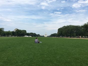 People on grassy field in park against sky