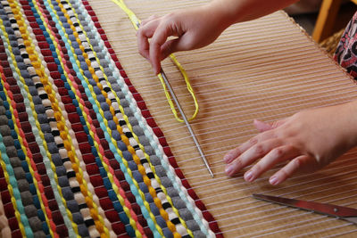 Cropped hands of woman weaving at workshop