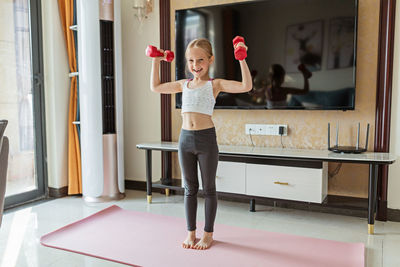 Full length of girl exercising at home