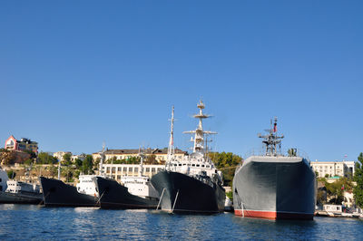 Sailboats in river against clear blue sky