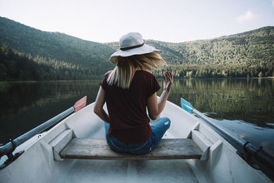 Rear view of woman sitting on boat against lake