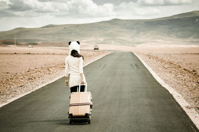 Rear view of woman walking on road in desert