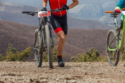Male athletes walk uphill with their mountain bikes