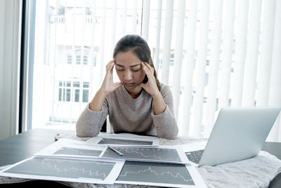 Young woman using mobile phone while sitting on table