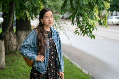 Beautiful young woman standing near the road with backpack 