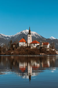 Island on the lake against clear blue sky with mountains in the background