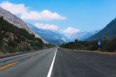 Empty road by mountains against sky