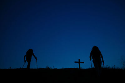 Silhouette men standing on field against clear blue sky