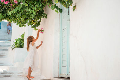 Rear view of woman standing against white wall