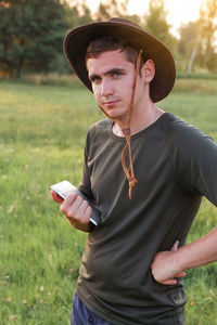 Young man farmer in cowboy hat at agricultural field on sunset holding tablet. portrait of happy man 