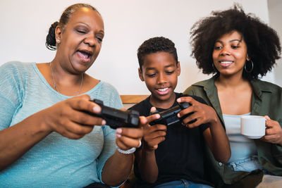 Family playing video game while sitting on sofa at home