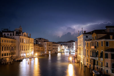 Canal amidst illuminated buildings in city at night