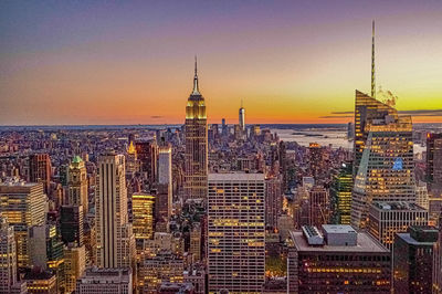 Modern buildings in city against sky during sunset