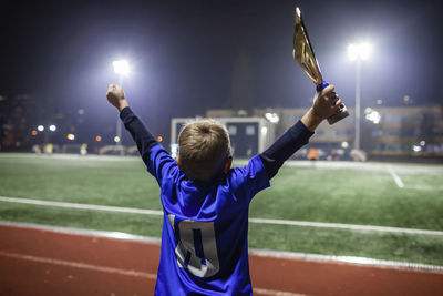 Young soccer player in blue jersey with ten number holding  winners cup after winning goal