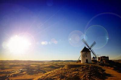 Traditional windmill on landscape against bright sun