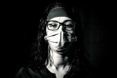 Close-up portrait of woman wearing mask against wall