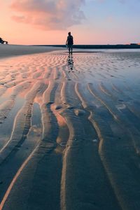 Silhouette man standing on beach against sky during sunset