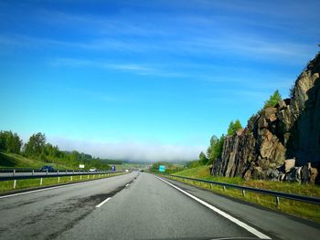 Road amidst trees against blue sky