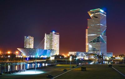 Illuminated cityscape against sky at night