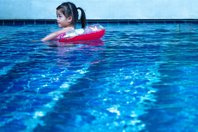 Girl with inflatable ring swimming in pool