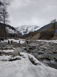 People on snowcapped mountain against sky