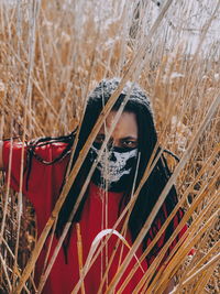 Portrait of man wearing mask amidst plants on field